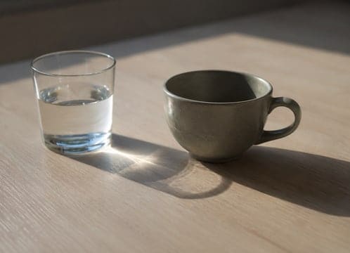 Una taza y un vaso de agua sobre la mesa de la consulta al terminar el día